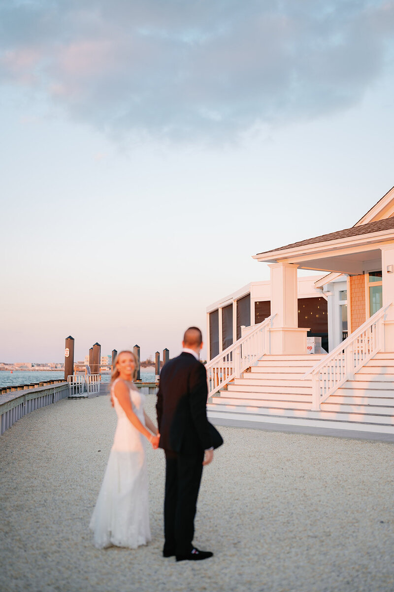 Couple kisses during sunset portraits on the bay at their Avalon Yacht Club wedding