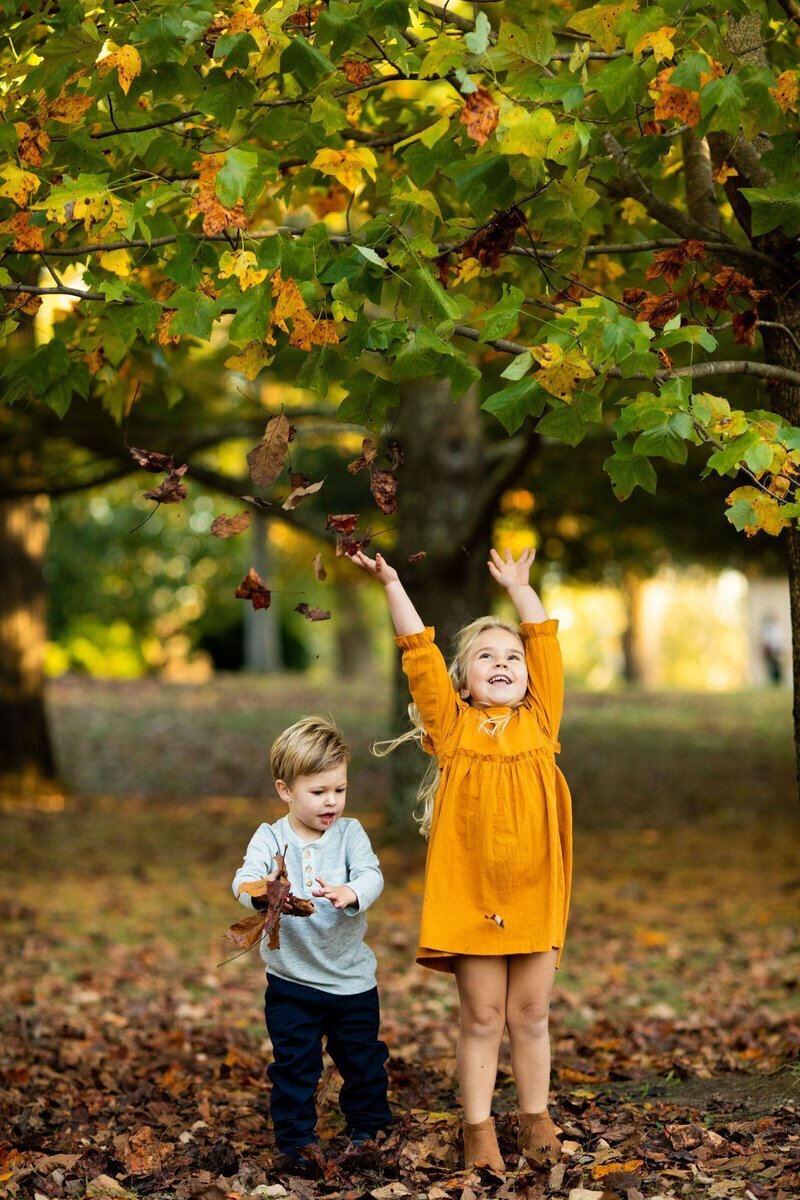 Kids throwing fall leaves taken by family photographer nj
