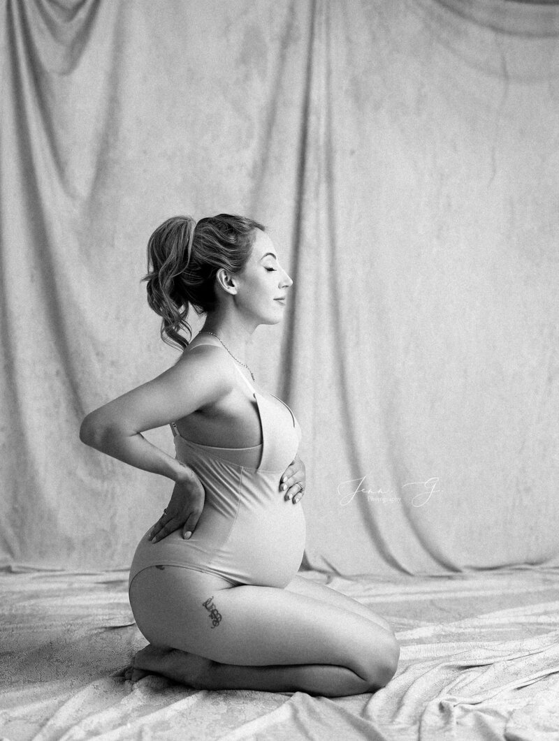 A pregnant women is posed in a black and white photo for a photographer in Coquitlam