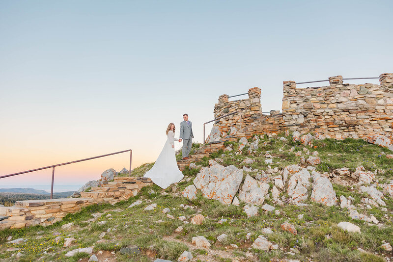 Bride and groom eloping in the breathtaking Snowy Range Mountains of Laramie, Wyoming, beneath stunning cotton candy skies, celebrating their love in a picturesque setting.