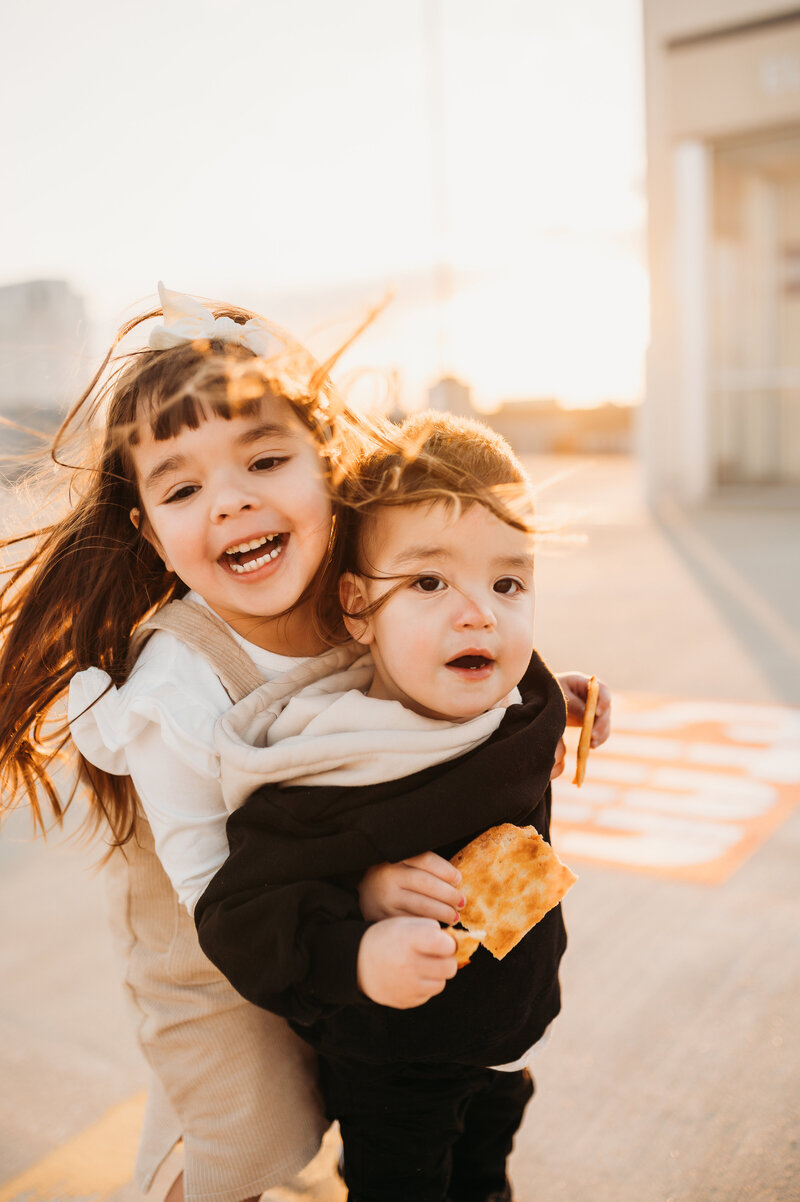 Toddlers playing on a rooftop parking garage at sunset.
