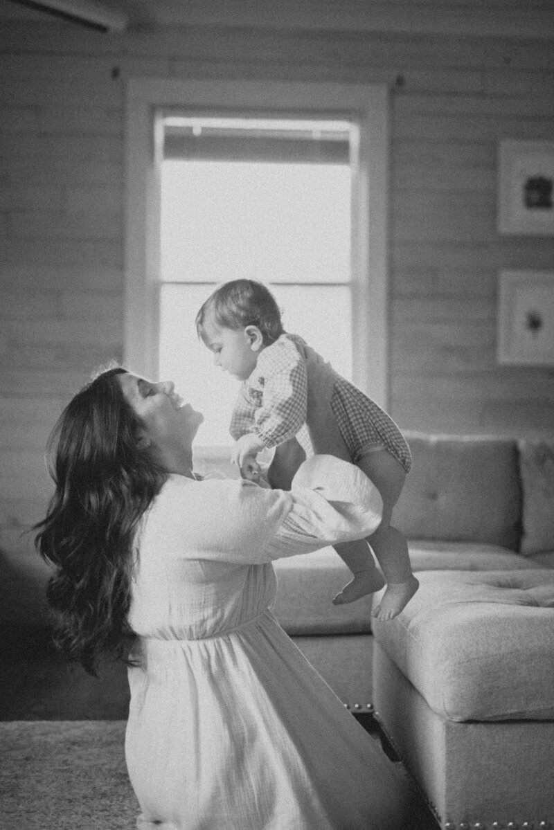 women holding baby up with sunlight behind her knoxville tennessee newborn photographer