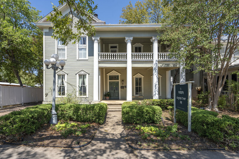 1880s white Victorian House with 4 classical columns shaded by trees