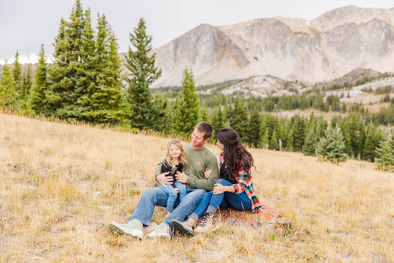 Joyful family posing together during their outdoor session amidst the breathtaking backdrop of the Snowy Range Mountains near Laramie, Wyoming.