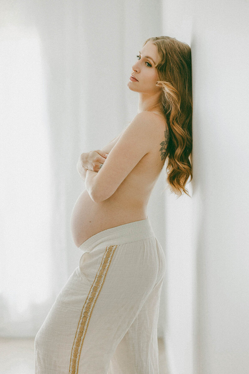 Light-filled maternity portrait of an expectant mother in linen pants, in a minimalist studio—elegant and timeless. Fort Collins maternity photo.