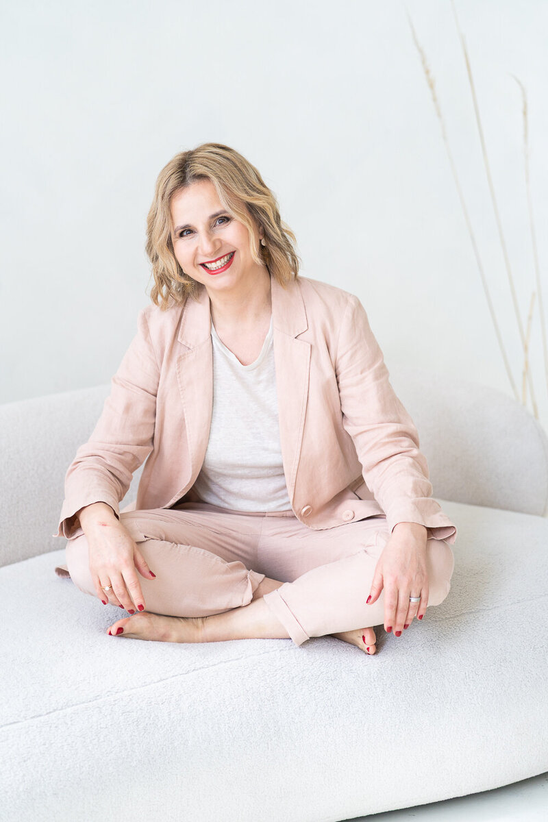 žena sedí na světlé pohovce a usmívá se