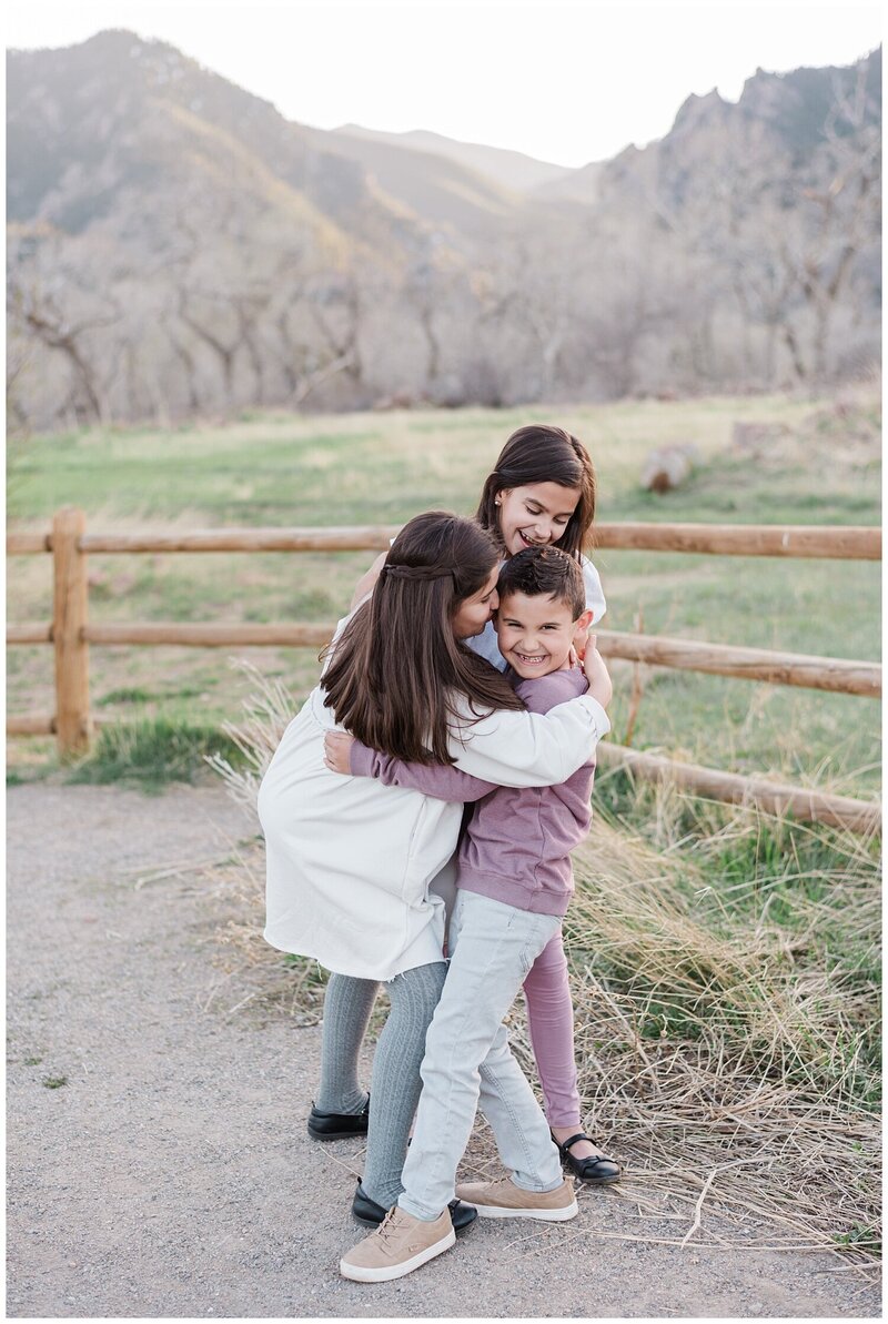 denver family photographer captures 3 siblings in a group hug with the Boulder flat irons in the background