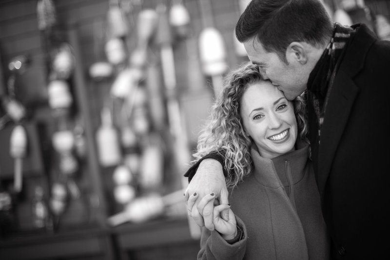 A black and white photo of an engaged couple sharing a tender moment in Boston during their engagement session, capturing the timeless romance of their connection against the city's historic charm.