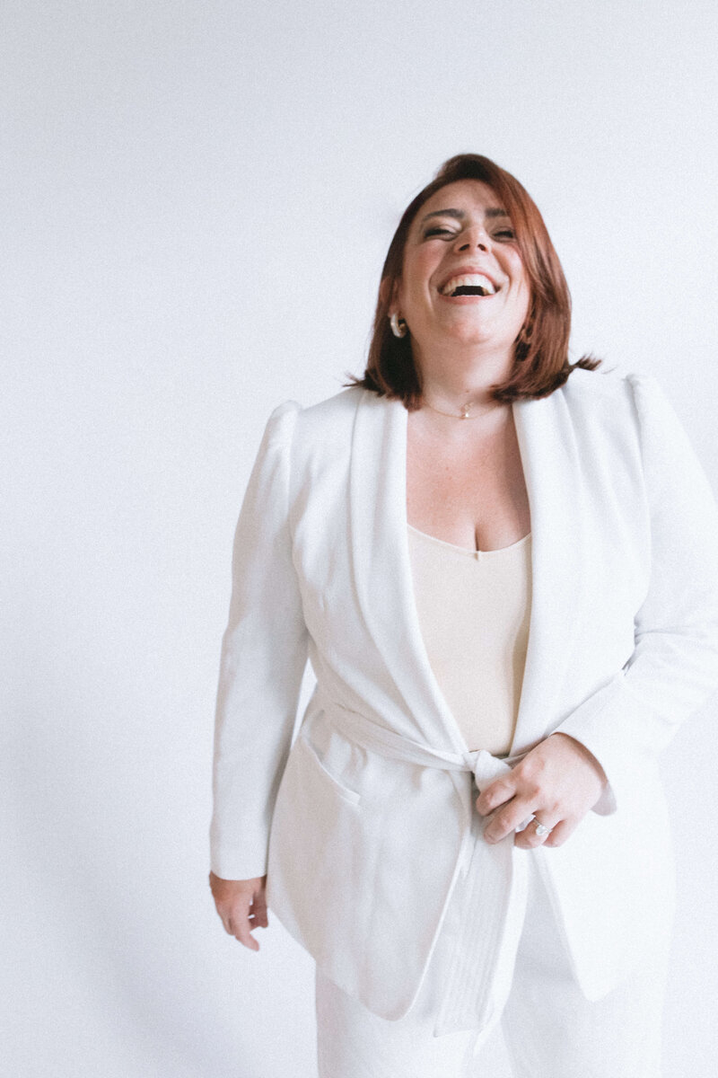 Casey, Founder of Most Valuable Bridesmaid smiling at the camera wearing white suit.
