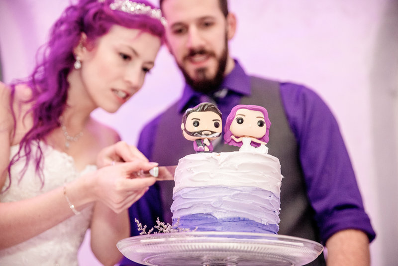 Bride and groom cut their cake with custom bobble heads