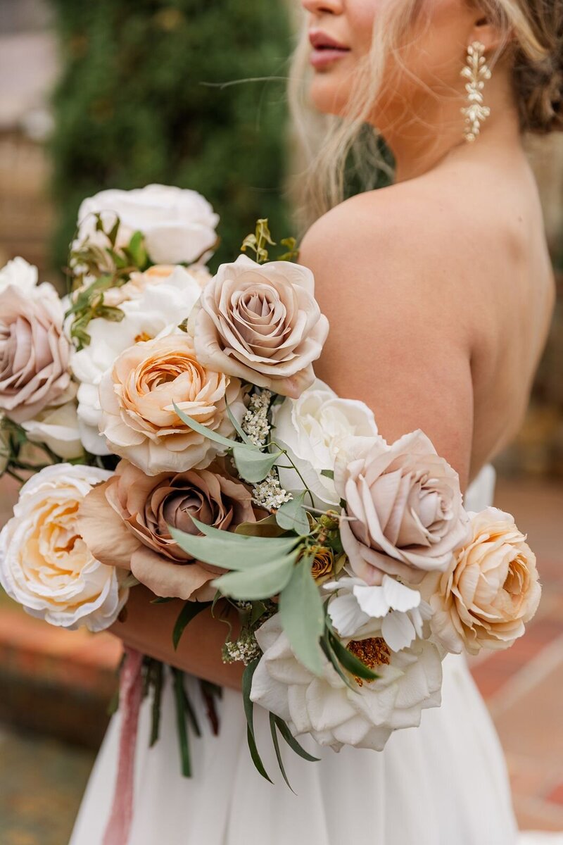 bride holding cream colored flowers in her arms