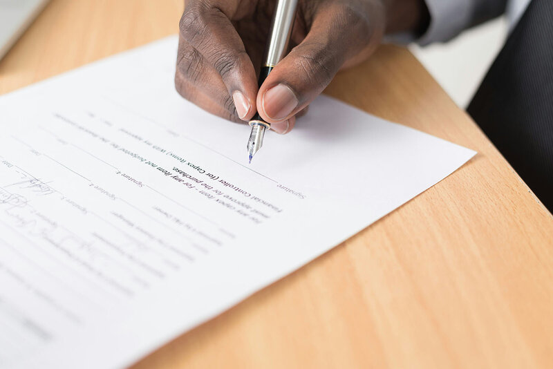 Stock photo of a hand signing a document. 
