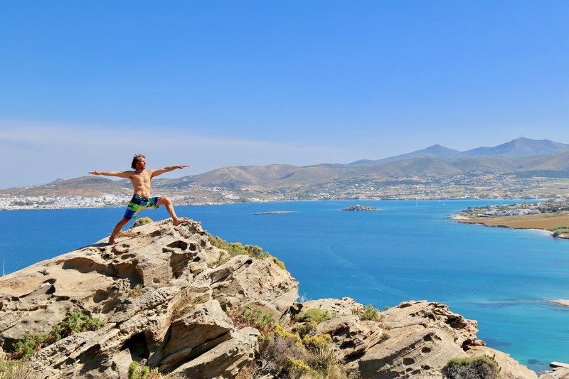 Shirtless Yogi on the Cliffs over Ocean in Warrior 2 pose