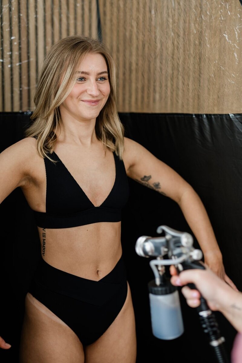 Woman in bikini receives an airbrush spray tan