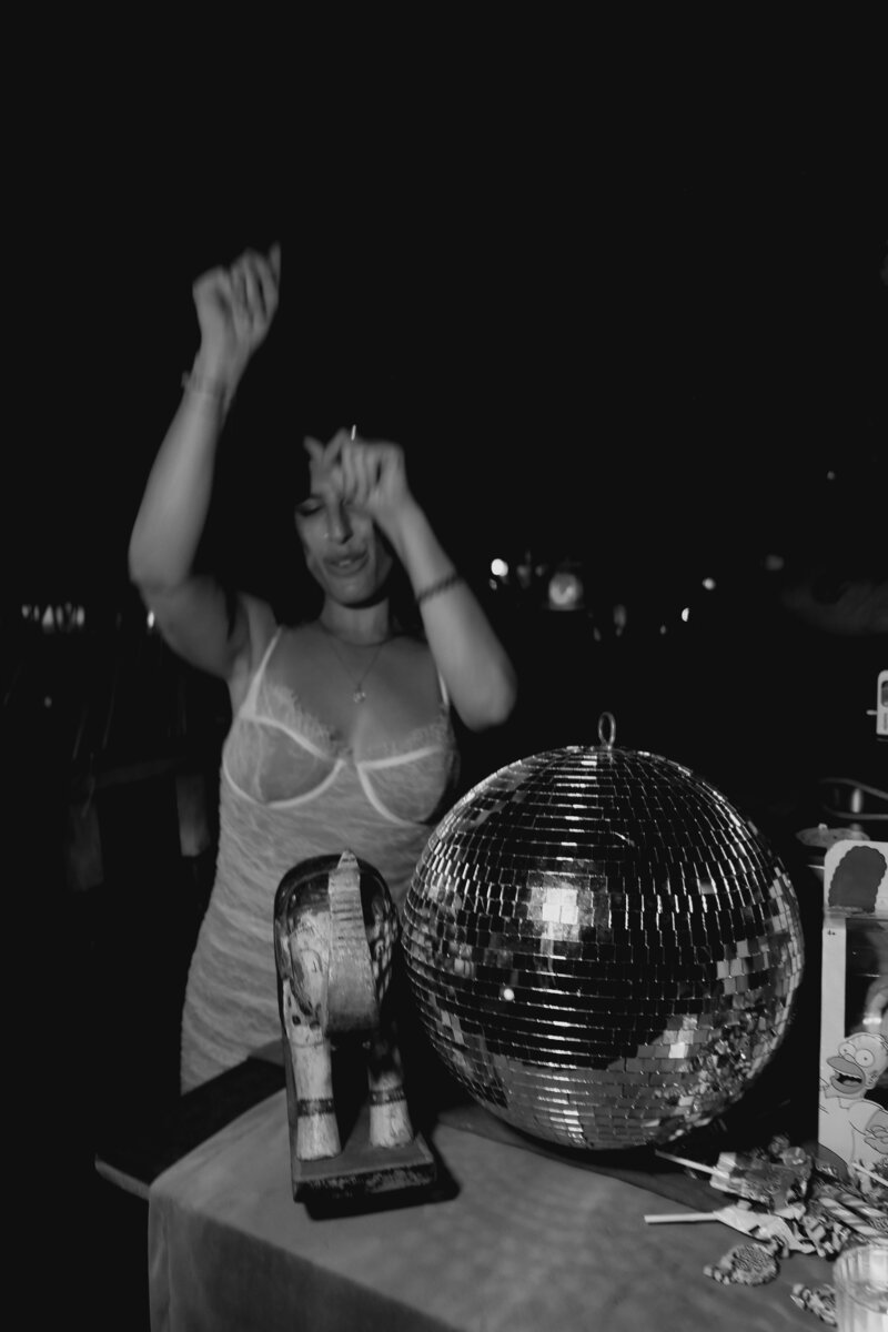 Black-and-white photo of Tristan Thibodeau dancing beside a disco ball, representing bold brand expression and creative energy at Wild Woman Haus®.