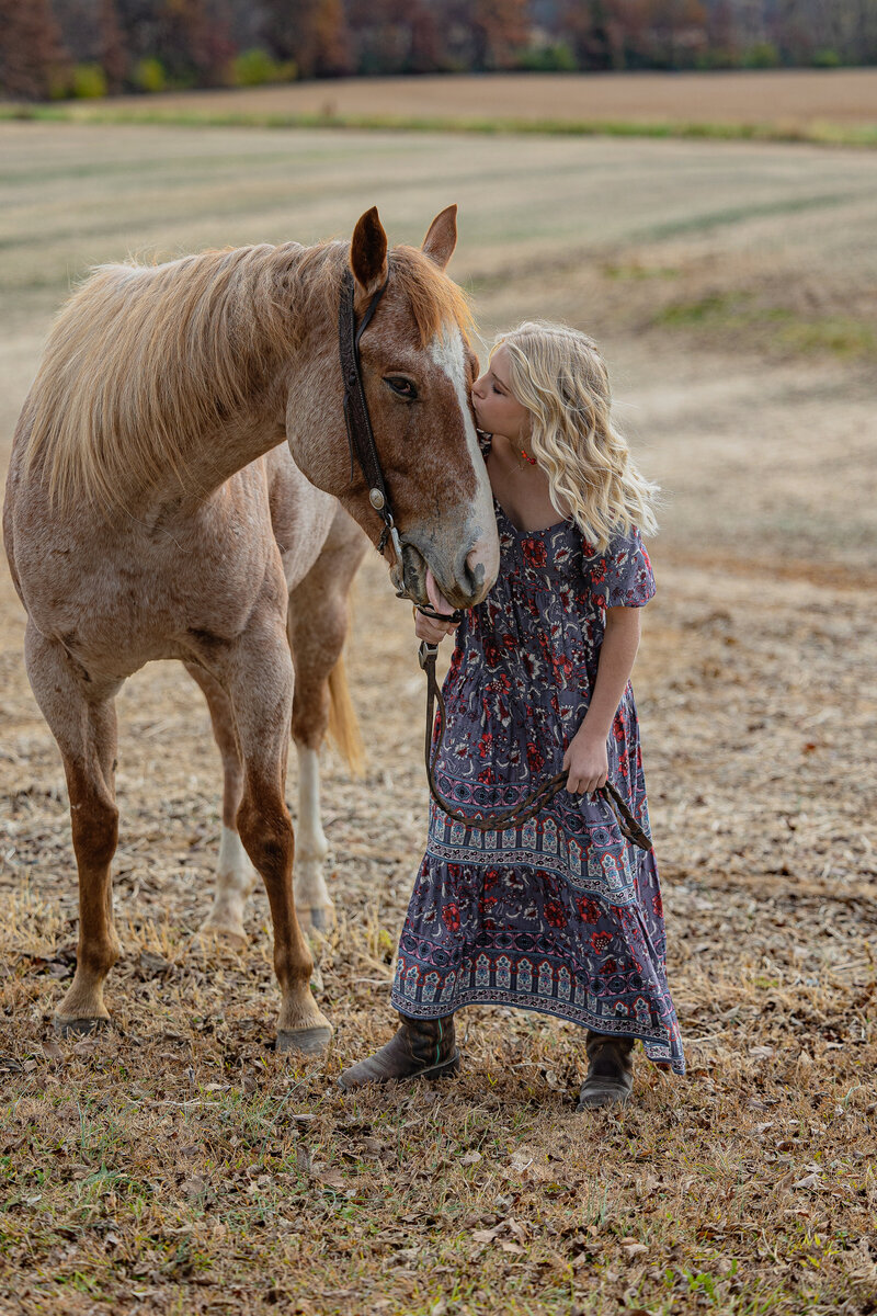 Young girl giving horse a kiss in field