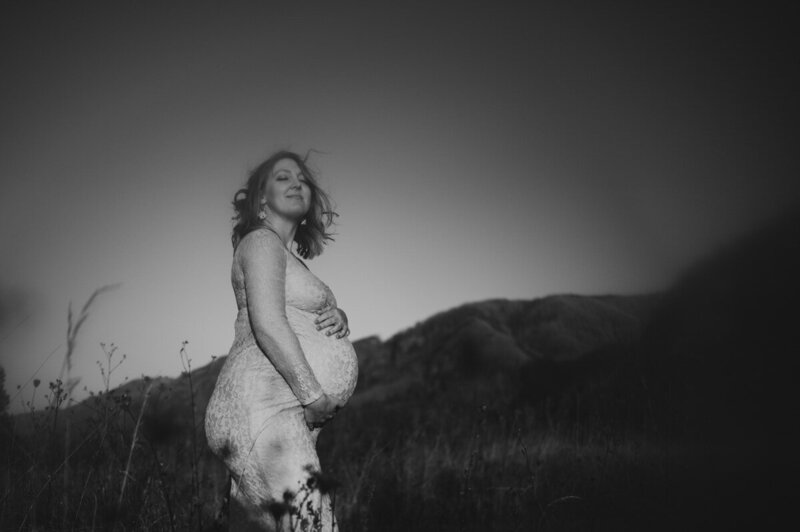 Woman sitting on a golden field during maternity session with Portland maternity photographer