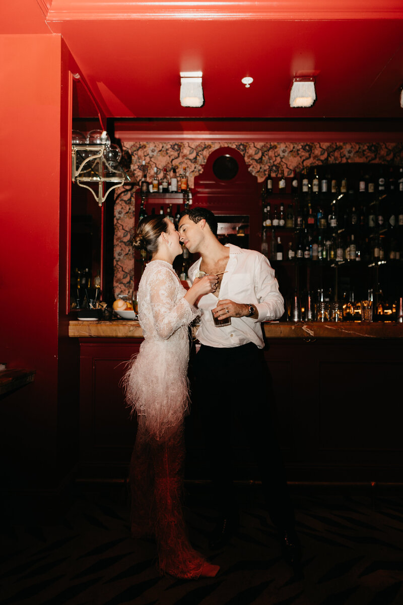 Bride seated on a vintage red chair in moody studio setting