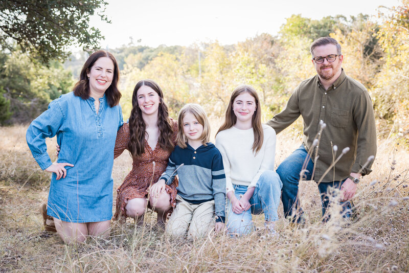 family posing in tall grass