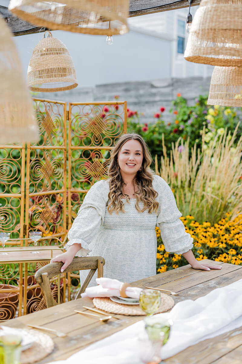 The owner and lead planner of Sustainable Soirees posing next to a beautifully designed tablesetting