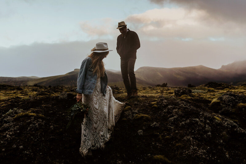 married couple is walking on a lava field in the Icelandic highlands during sunset hours