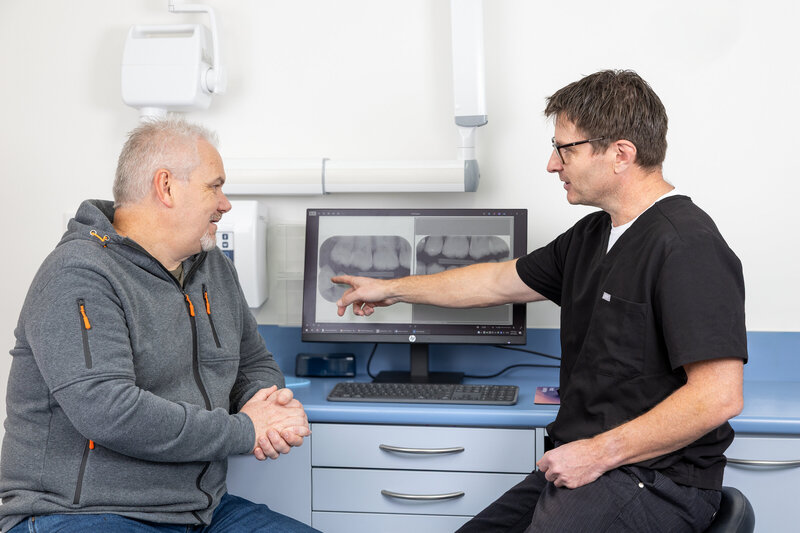 Patient and dentist discussing treatments while looking at teeth x-rays