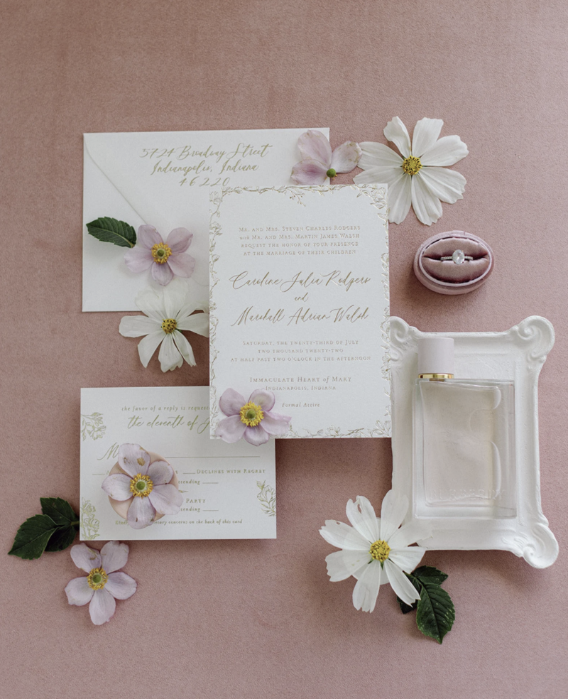 Light pink suede mat with blush-toned invitations and florals