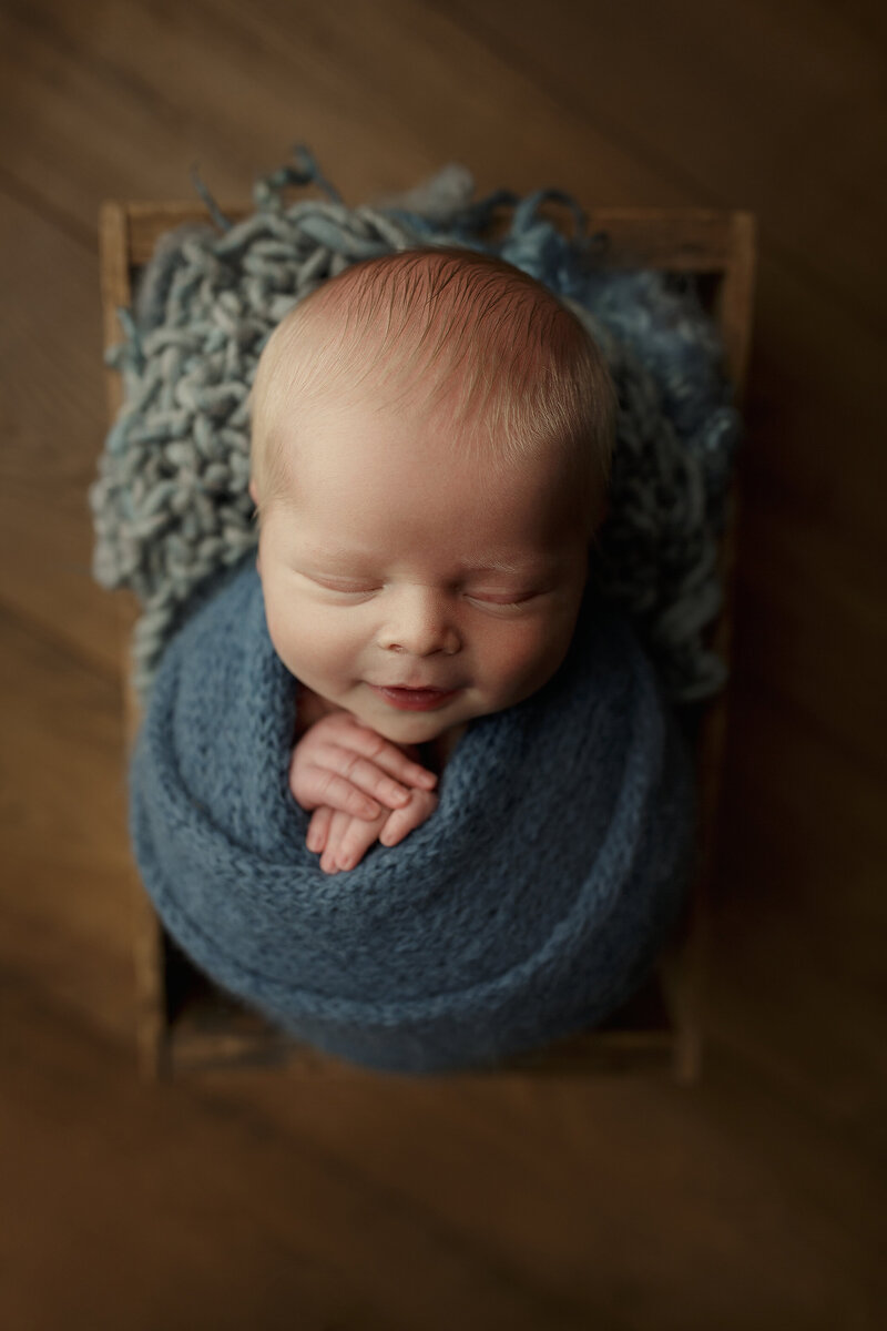 Infant boy wrapped in blue.