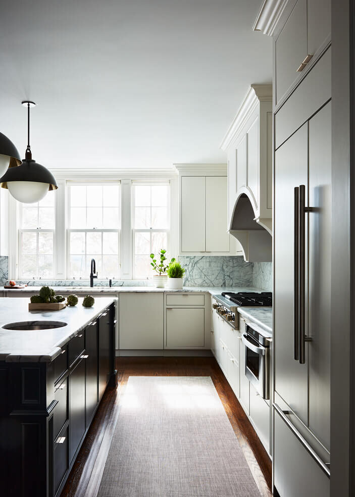Historic home designer renovates a kitchen with white cabinets, a bold black island, and a luxury light fixture by Allied Maker, blending classic and modern design.