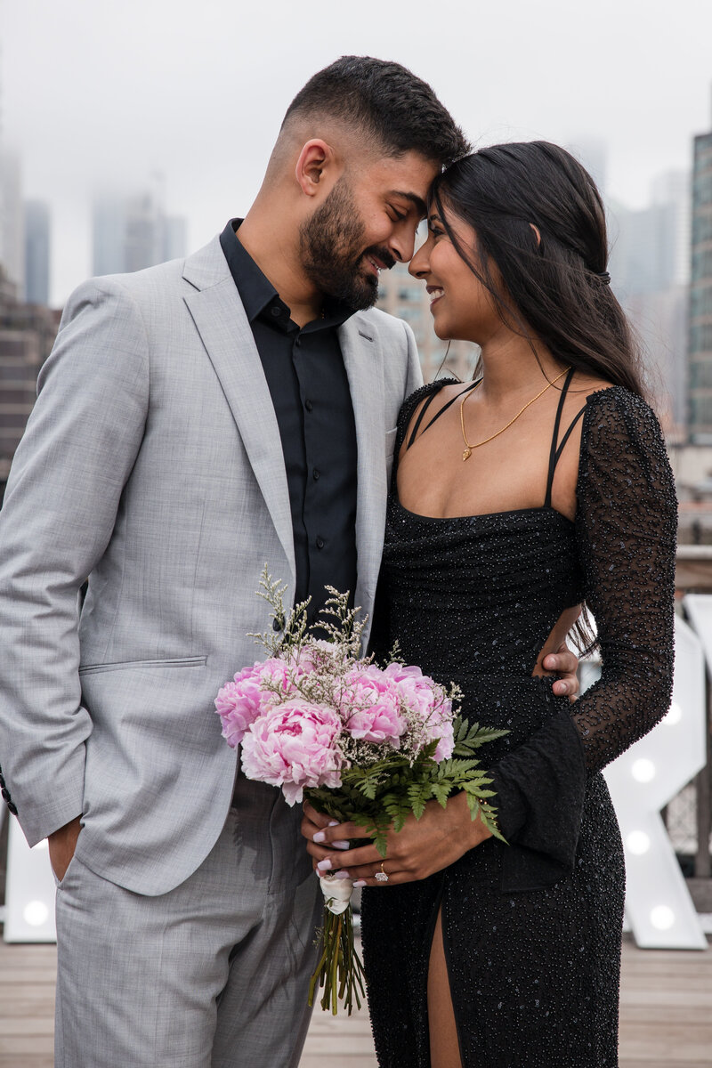 Young Indian couple dressed in black tie embracing in a portrait after the wedding proposal.