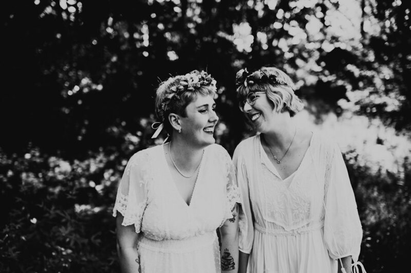 lesbian queer couple holds hands and laughs together during wedding portrait session with linnsej photography