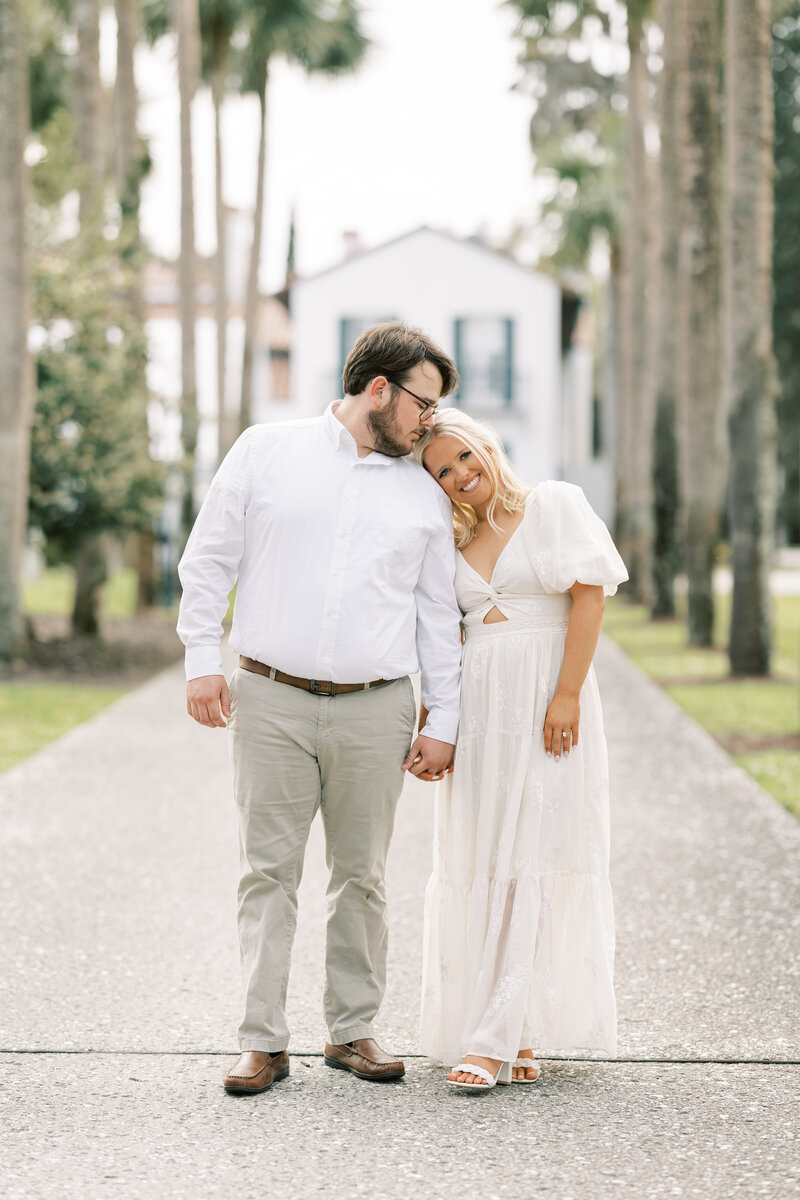 man kissing his fiance on the head while they stand in the driveway of a Georgia home