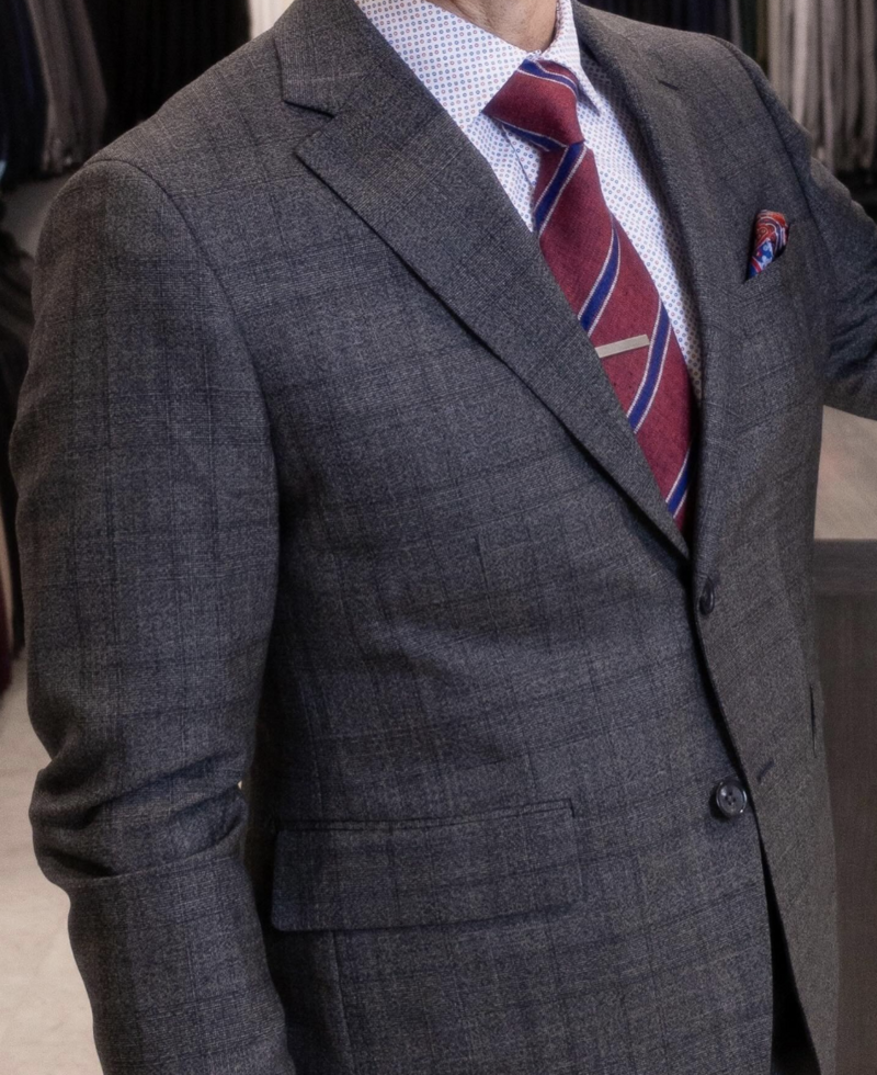 A man wearing sharp suit accessories, including a tie bar and pocket square