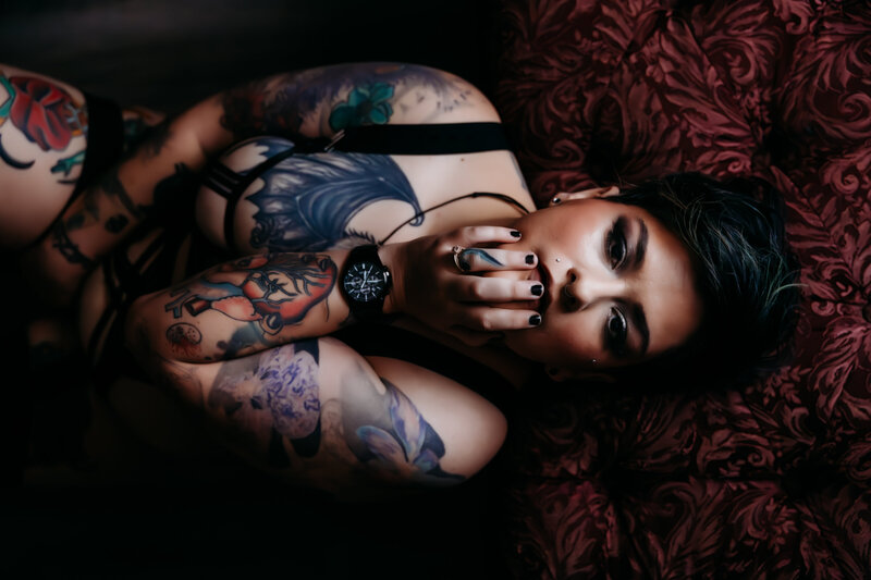 Boudoir photography woman in black bodysuit on red vintage couch with tattoos in Amarillo TX