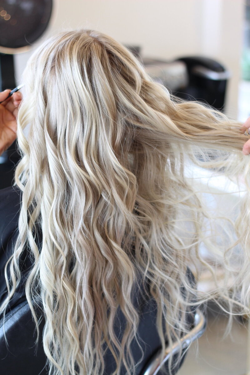 Two hairstylists taking photos of hair extensions