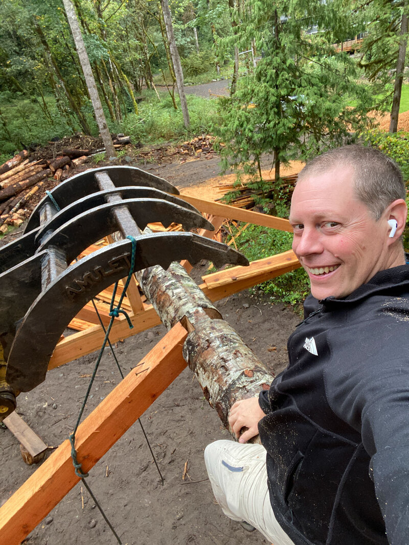 Michael smiling while moving logs with construction equipment