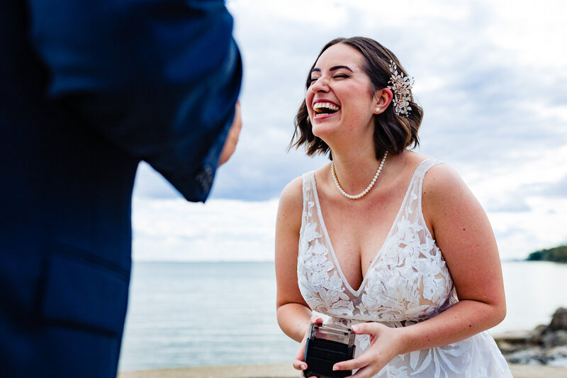 Bride laughing during the first look with her husband. Standing next to Lake Erie at the McIntyre in Monroe Michigan