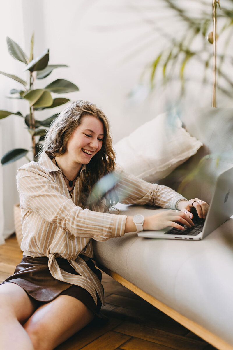 fotograf in münchen sitzt arbeitend mit laptop am sofa