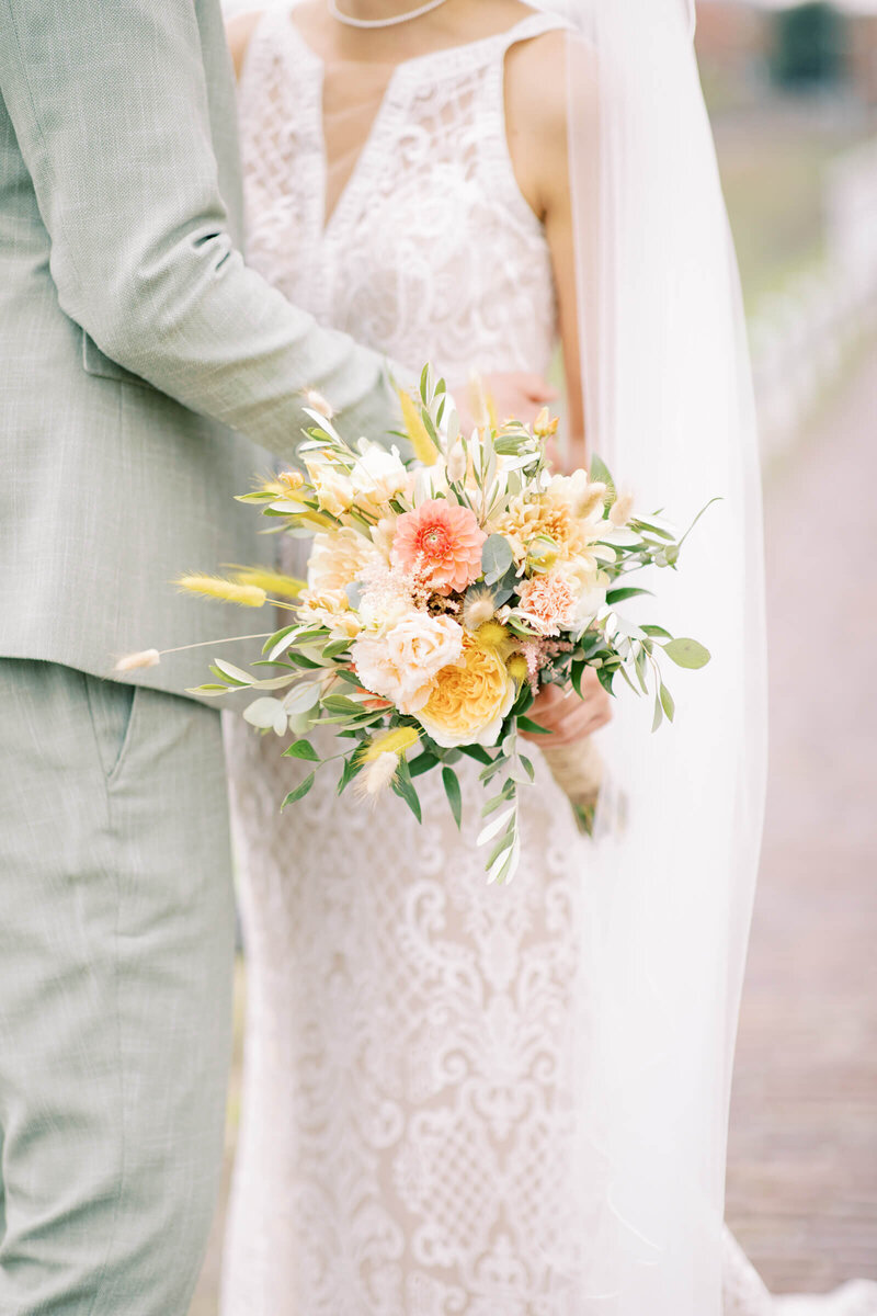 Een intieme close-up van een bruid met een kleurrijk boeket bloemen, vastgelegd in zachte en romantische tonen.