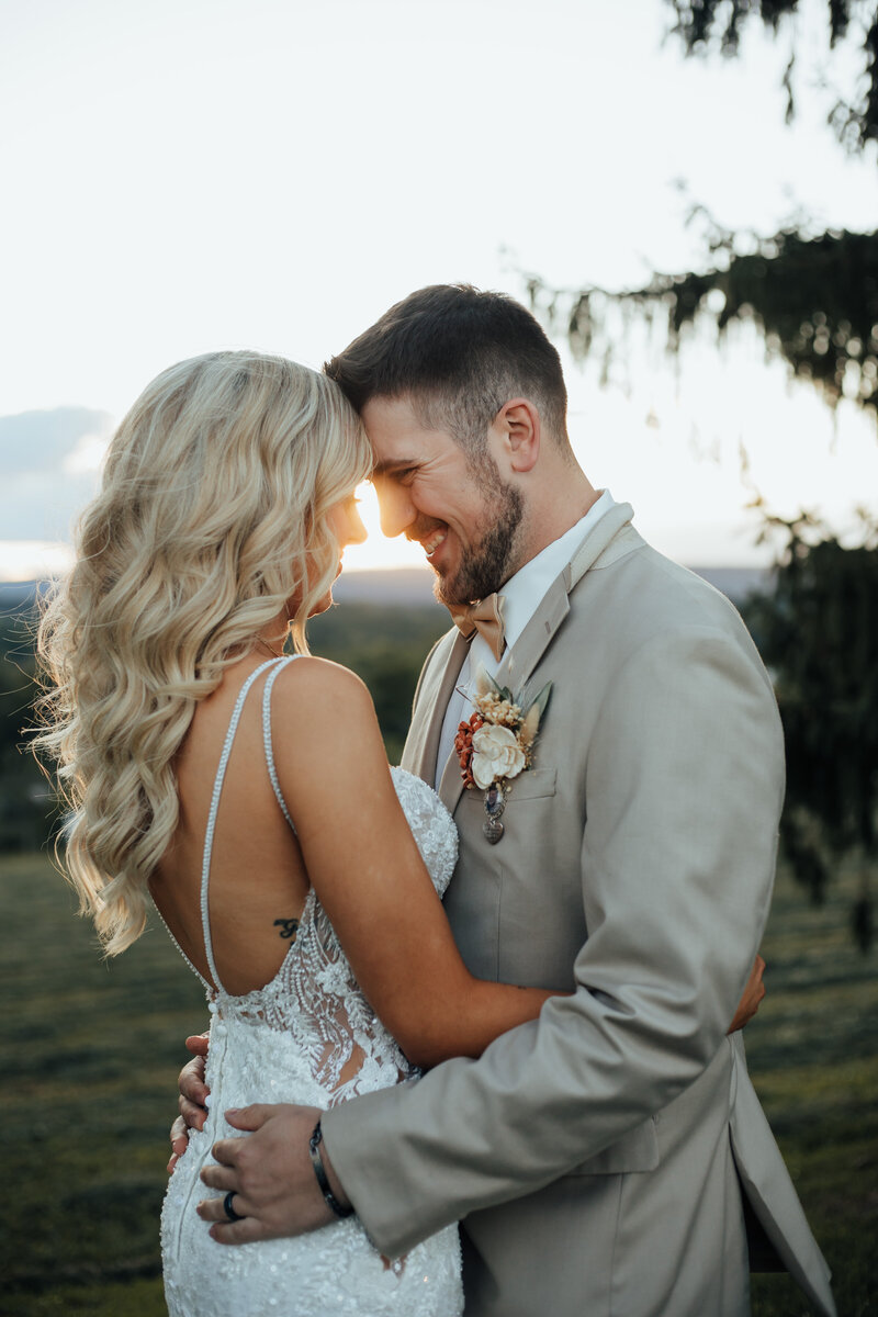 bride and groom hugging in field at sunset