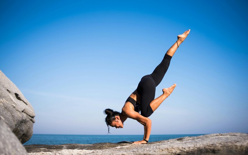 Traveler balancing in a yoga pose on the beach at sunrise, perfect for wellness and mindful escapes.