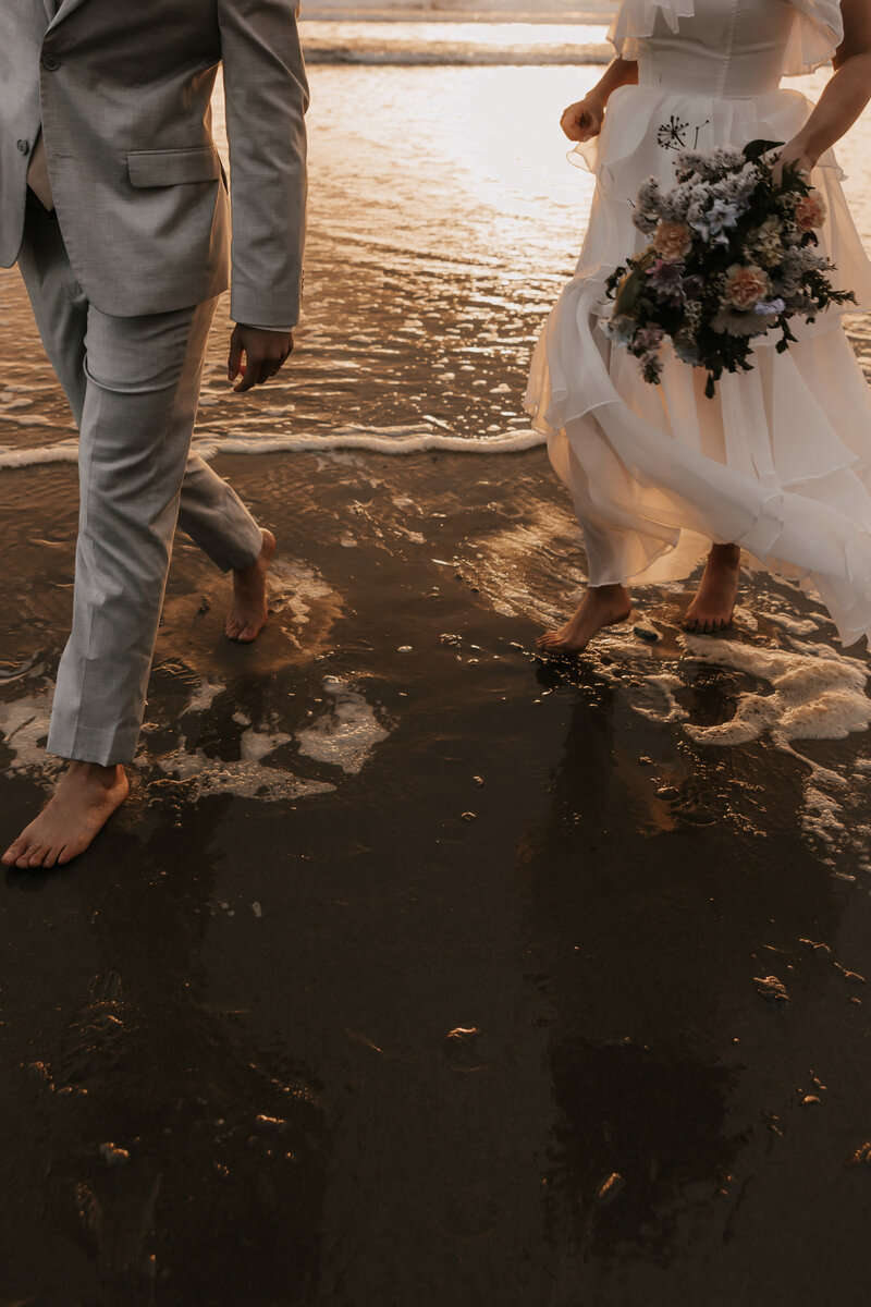 Bride and groom walking on the ocean shore
