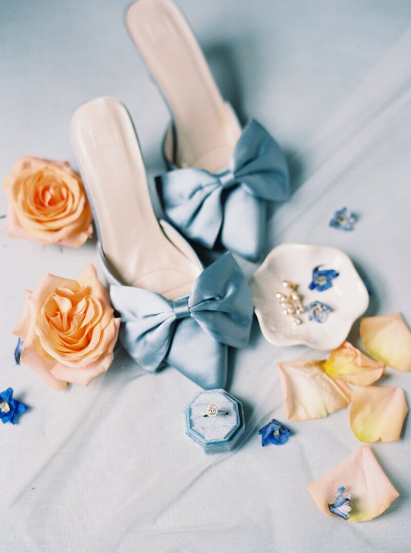 Elegant bridal detail of blue shoes with a bow, captured on film by Morgan Alysse, Louisiana film photographer.