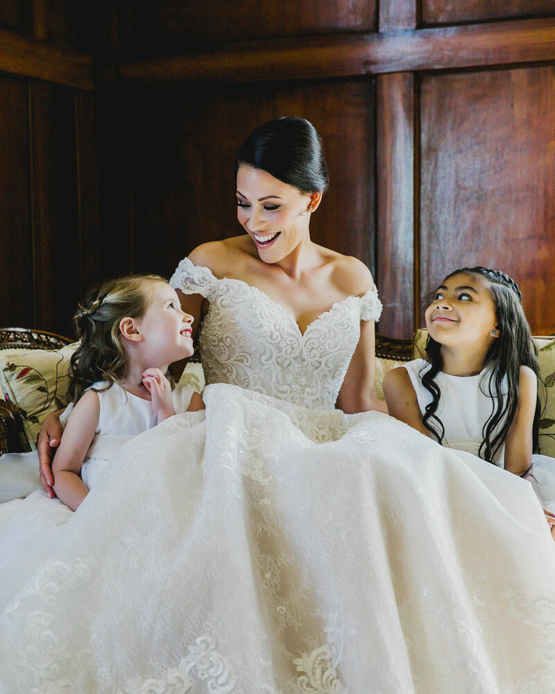 Bride smiling as she sits down with two young guests
