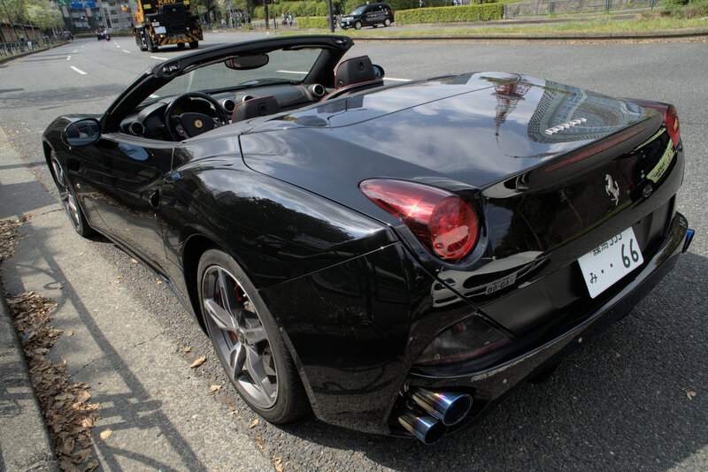 Rear view of a sleek black Ferrari California convertible parked roadside, showcasing luxury curves and dual exhaust—part of Tokyo Luxe Drive’s high-performance tour fleet.