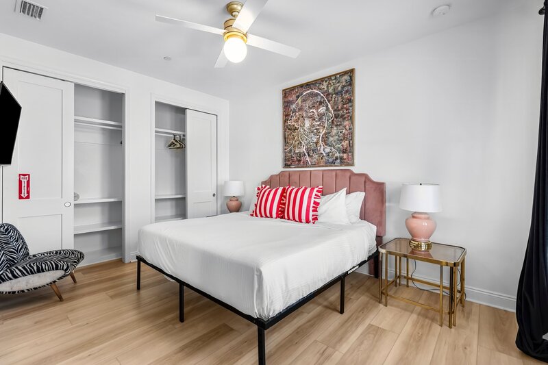 Spacious king bedroom with striped pillows, open closets, and bold decor—ideal for couples or groups visiting Panama City Beach or Alys Beach.