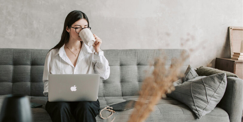 Woman on her laptop computer, taking a sip from a coffee mug