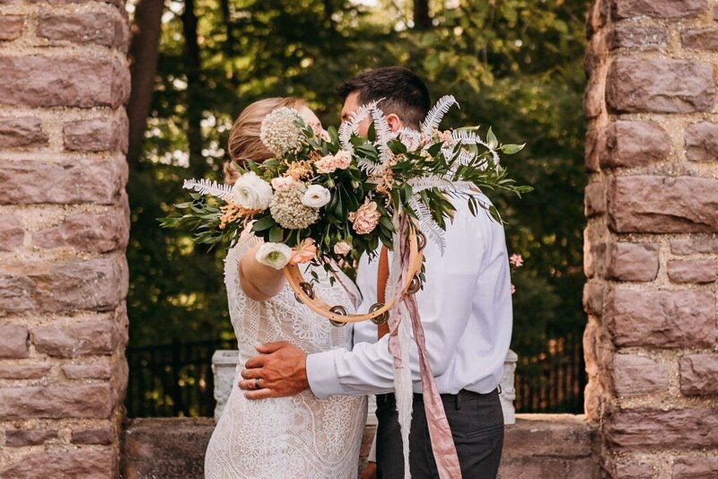 Wedding couple kiss behind a flower bouquet