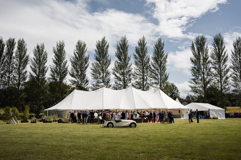 A large pole marquee in white with clear walls on a green lawn