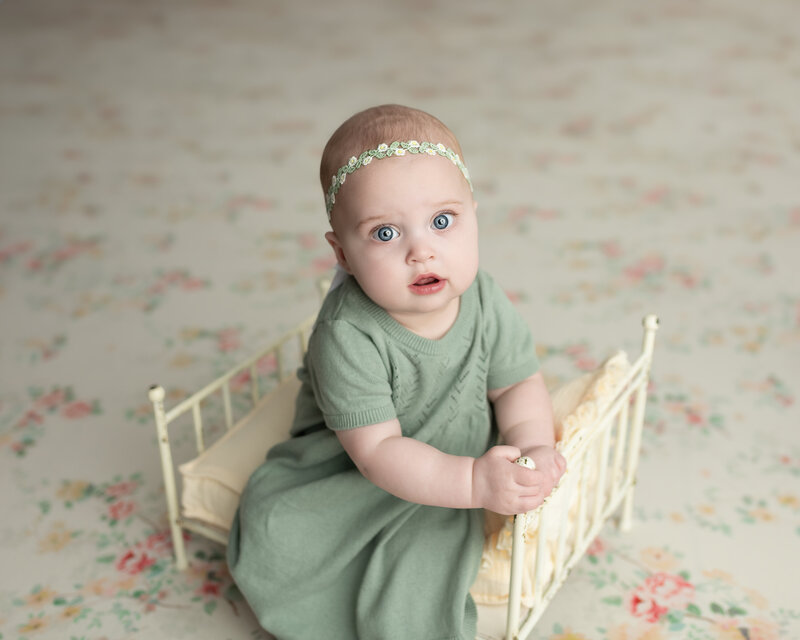 Delicate details and gentle styling come together in this vintage-inspired milestone portrait of a baby girl seated in a floral-themed set.